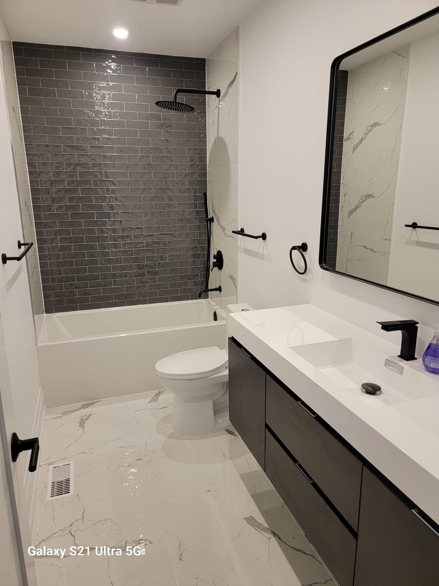 Modern bathroom with subway tile shower, marble floor and floating vanity