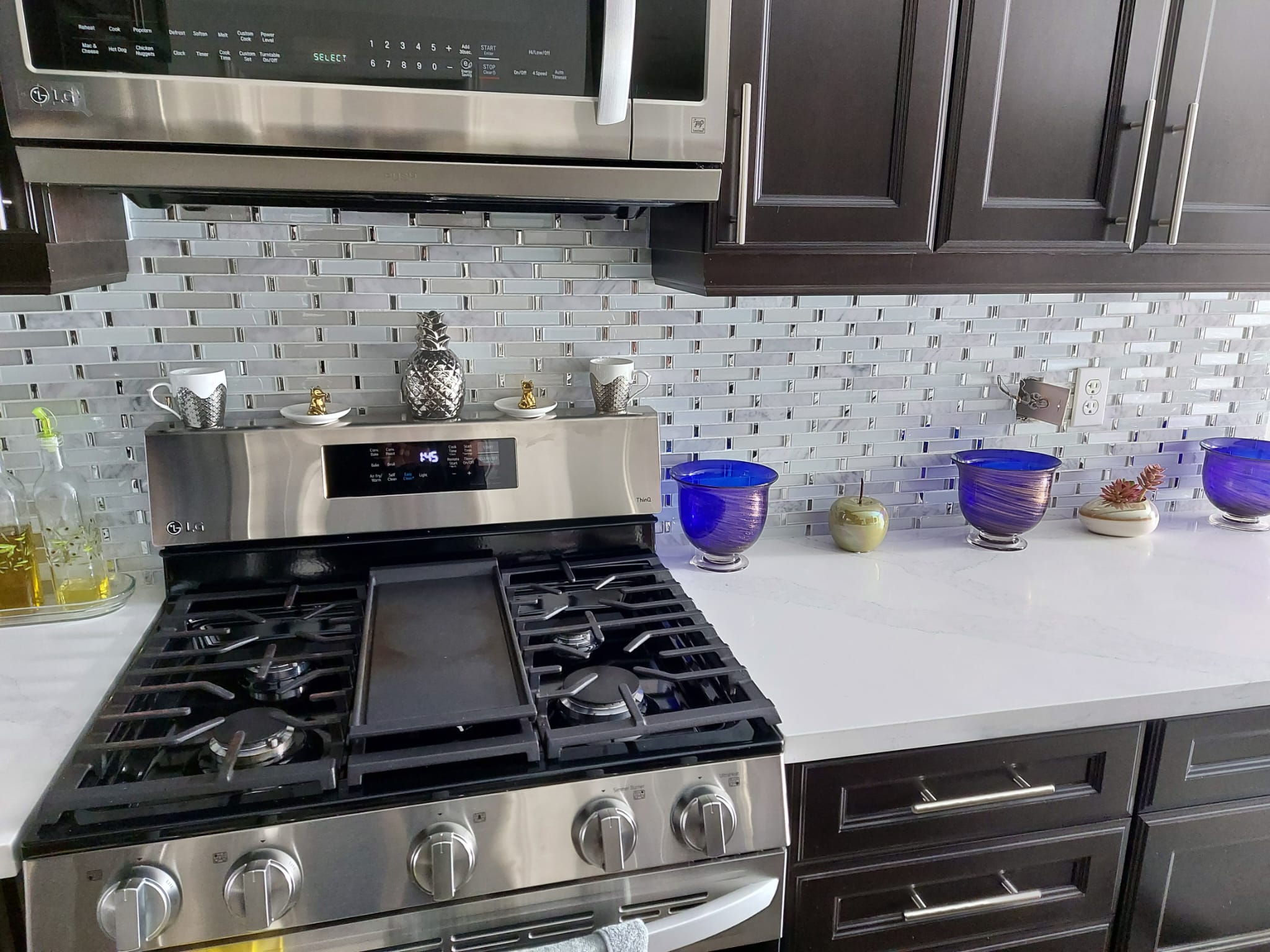Glass mosaic kitchen backsplash above a stainless gas range